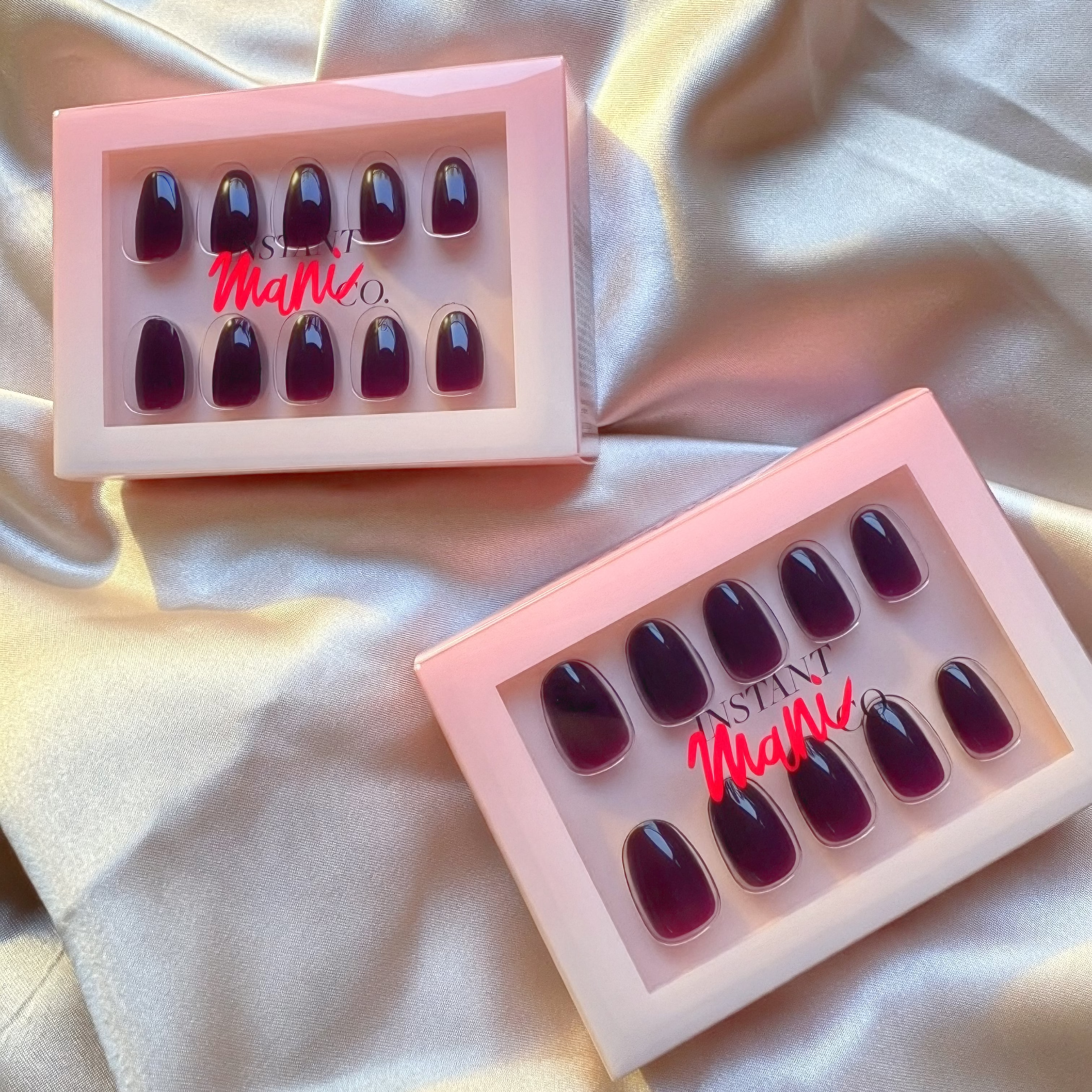 Two Instant Mani Co. press on nail packets in the shade plum