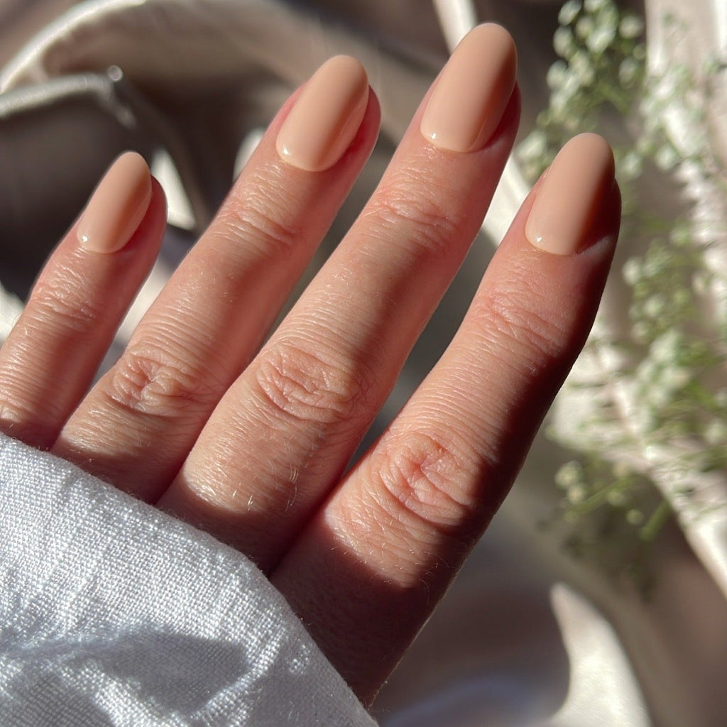 Girl wearing Instant Mani Co Allure neutral colour nails while wearing a white long sleeve top with silk background
