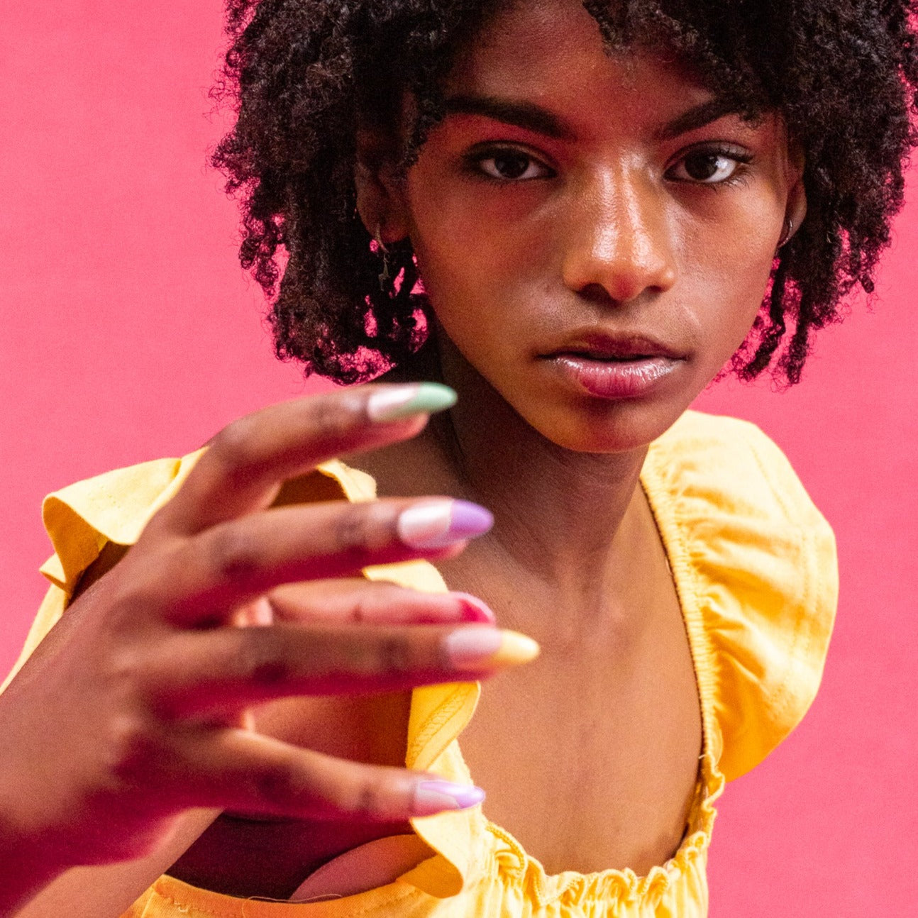 Girl wearing yellow top, with Instant Mani Co. rainbow coloured tip press-on nails