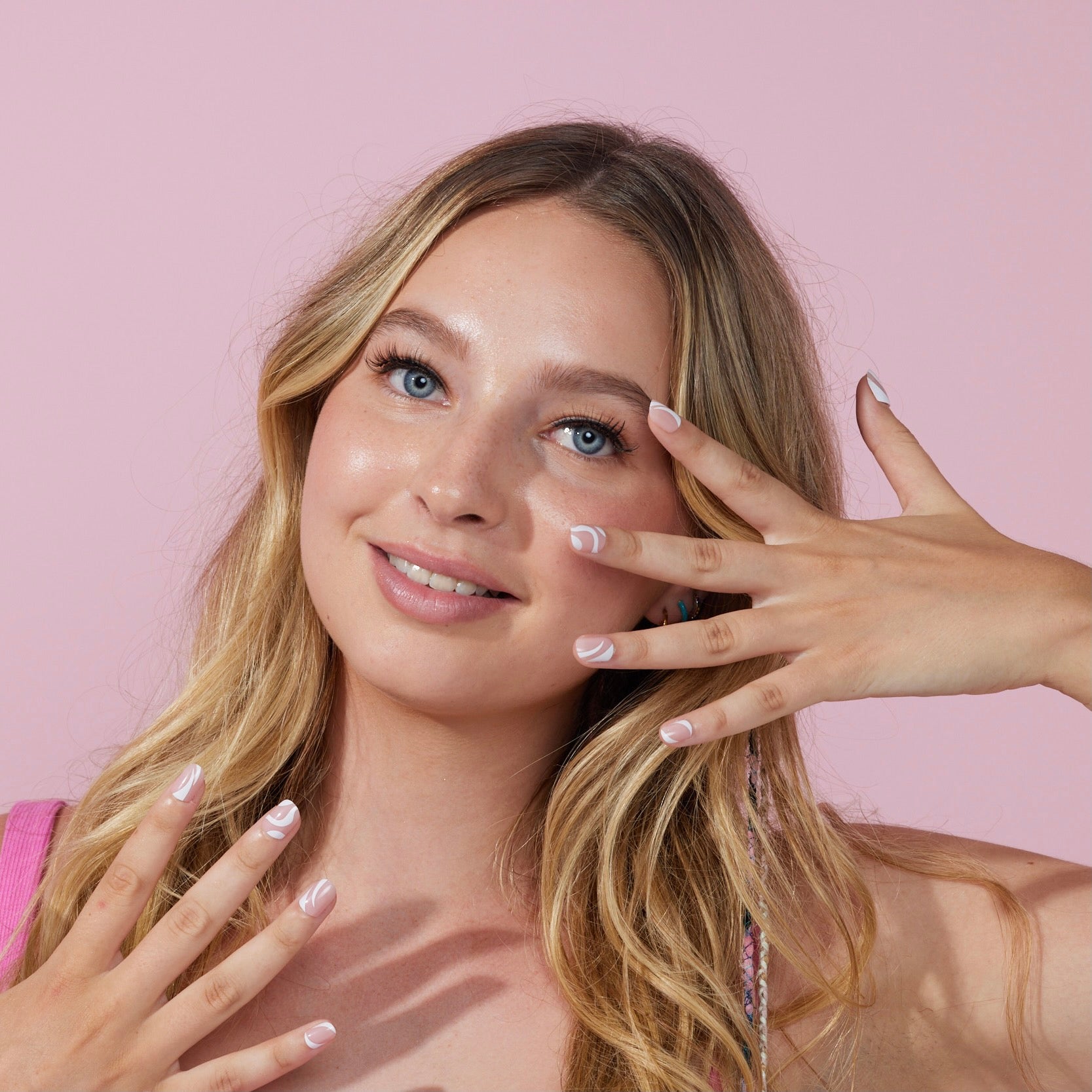 Girl standing in front of pink background wearing Instant Mani press on nails