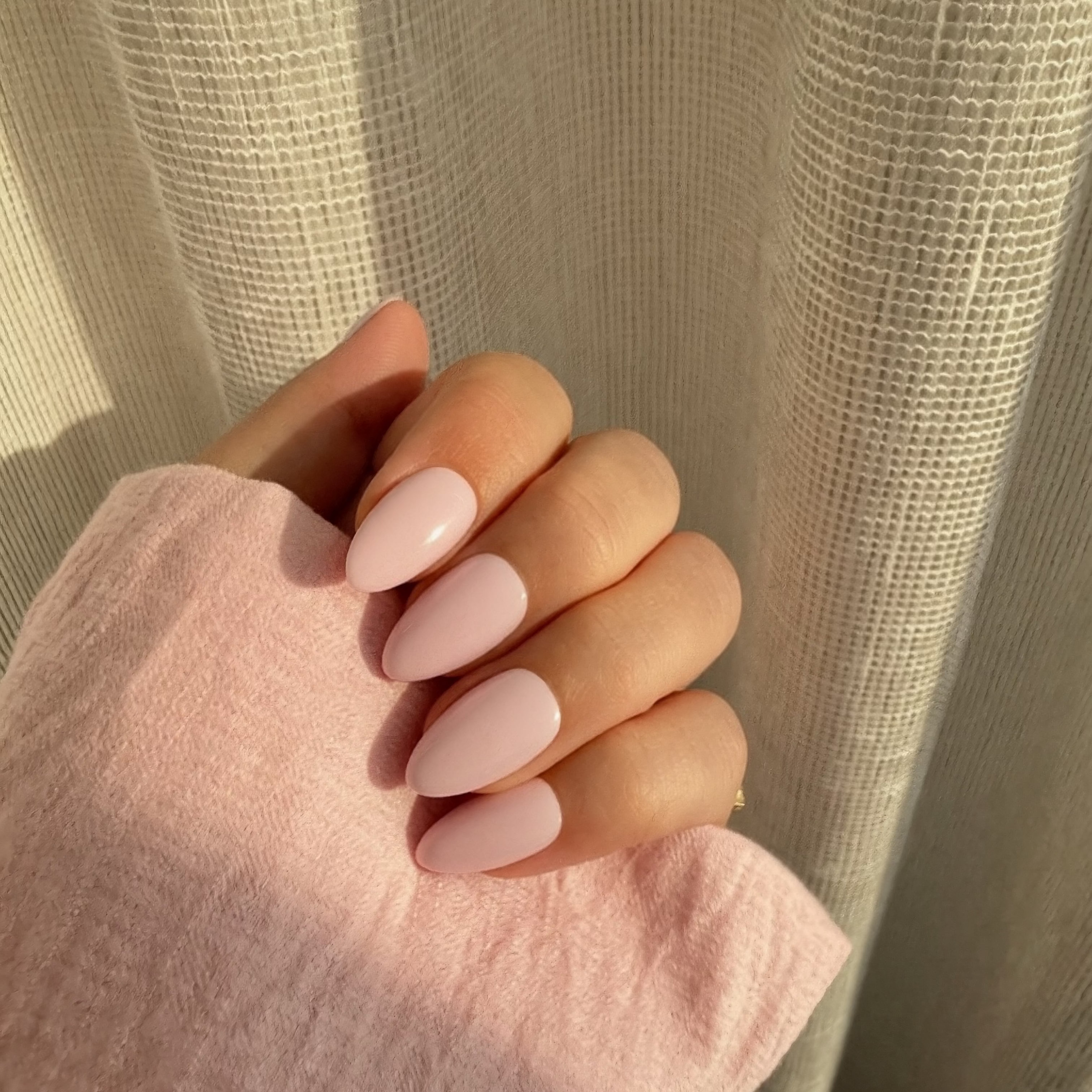 Hand with Instant Mani Co. pink peony press on nails against a neutral background