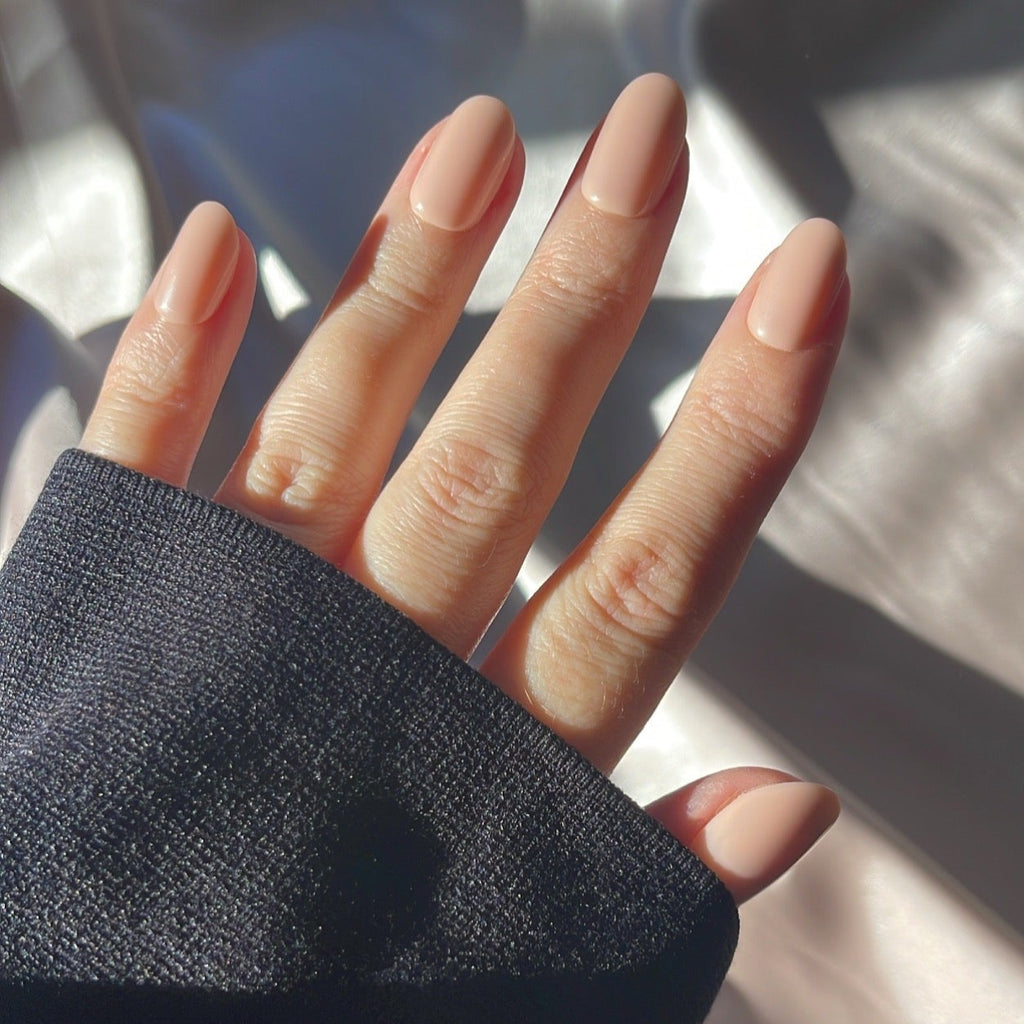 Girl wearing Instant Mani Co Allure neutral colour nails while wearing a black long sleeve top with silk background