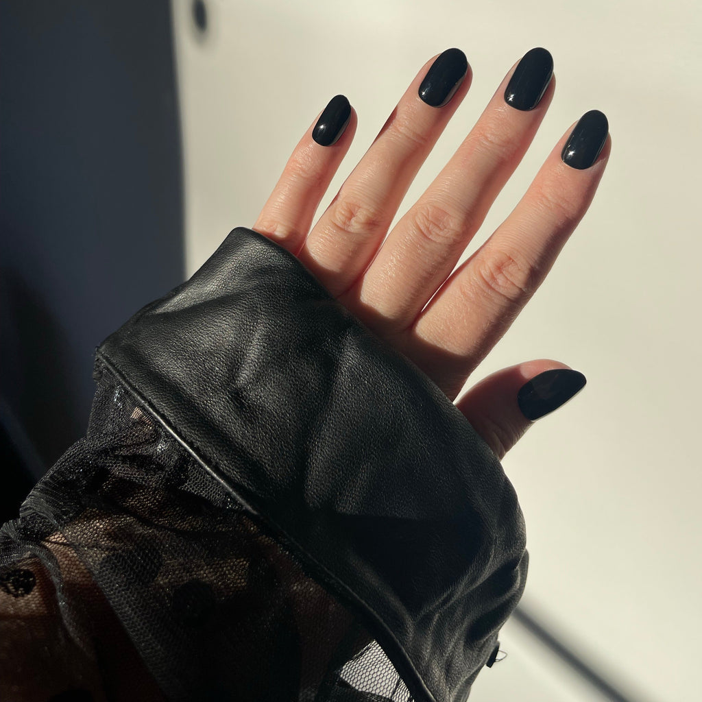Girl wearing Instant Mani Co caviar black press on nails, wearing long sleeved black top, in the sun