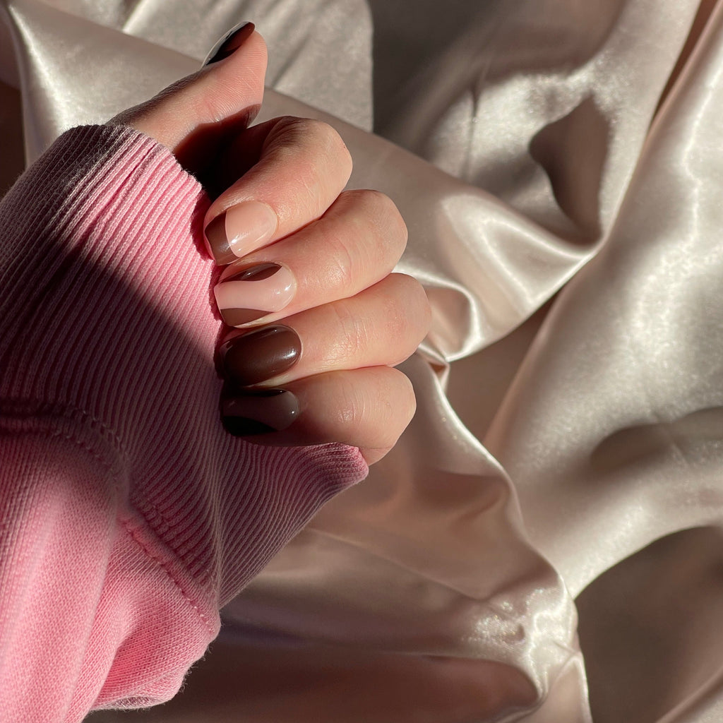 Girl wearing long sleeve pink top, also wearing Instant Mani Co Drama brown press on nails, with silk background