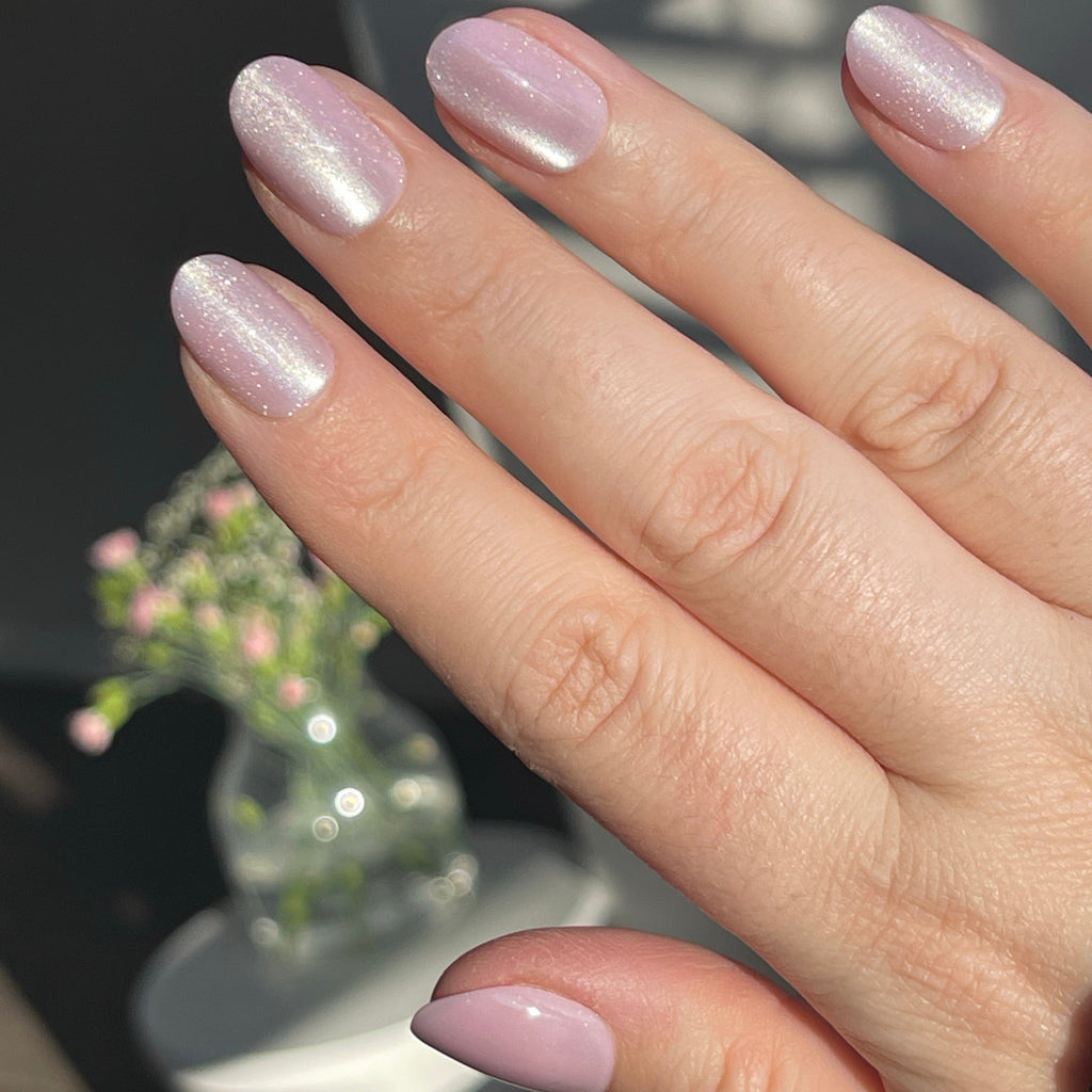 Girl wearing Instant Mani Co Bewitched velvet pink press on nails with flowers in the background