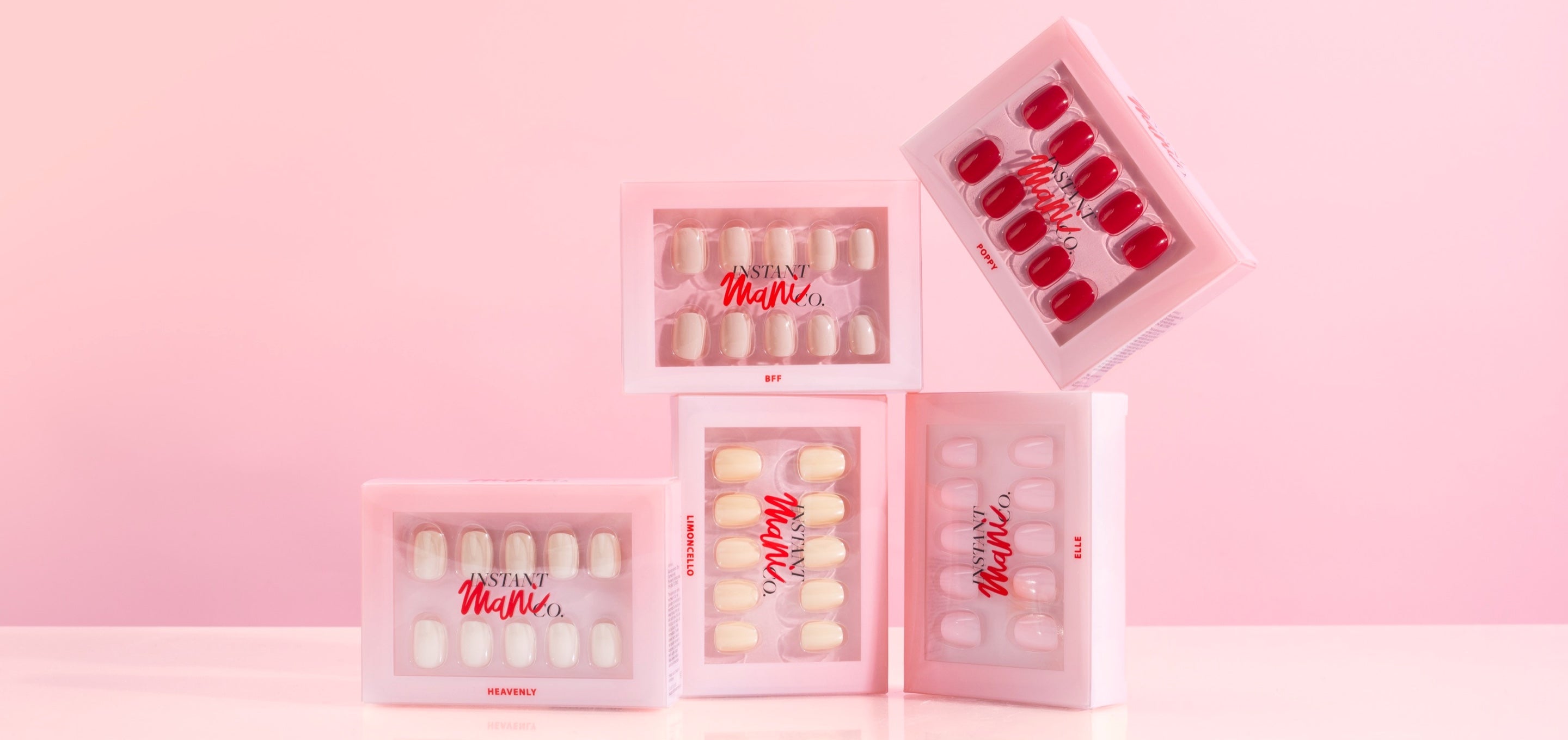 Instant Mani Co. press-on nail sets arranged on a pink studio background.