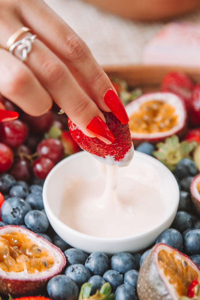 Instant Mani press-on nails in red, dipping strawberry into white chocolate fruit platter. 