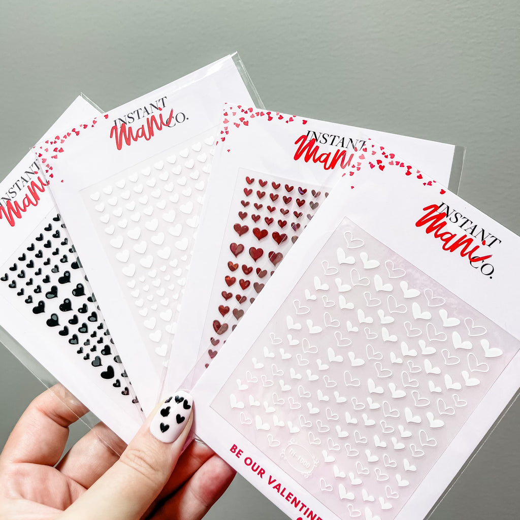 Person holding Instant Mani Co heart shaped nail stickers 