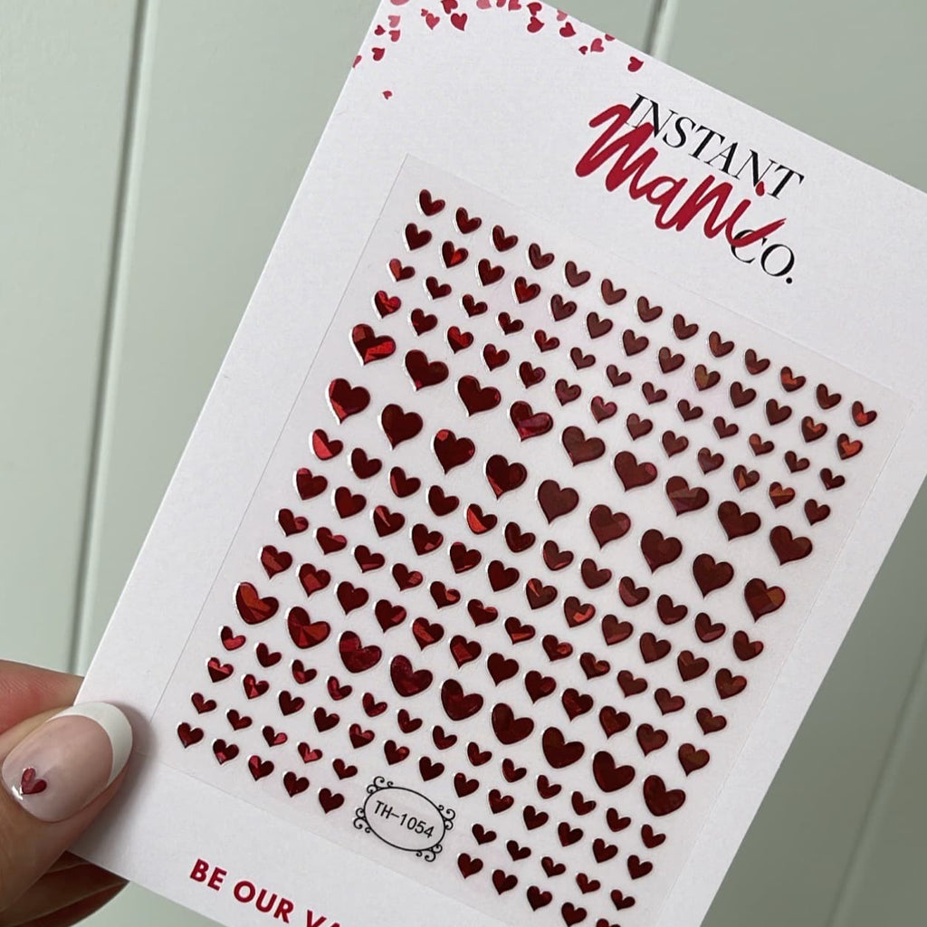 Person holding Instant mani Co. red heart shaped nail stickers