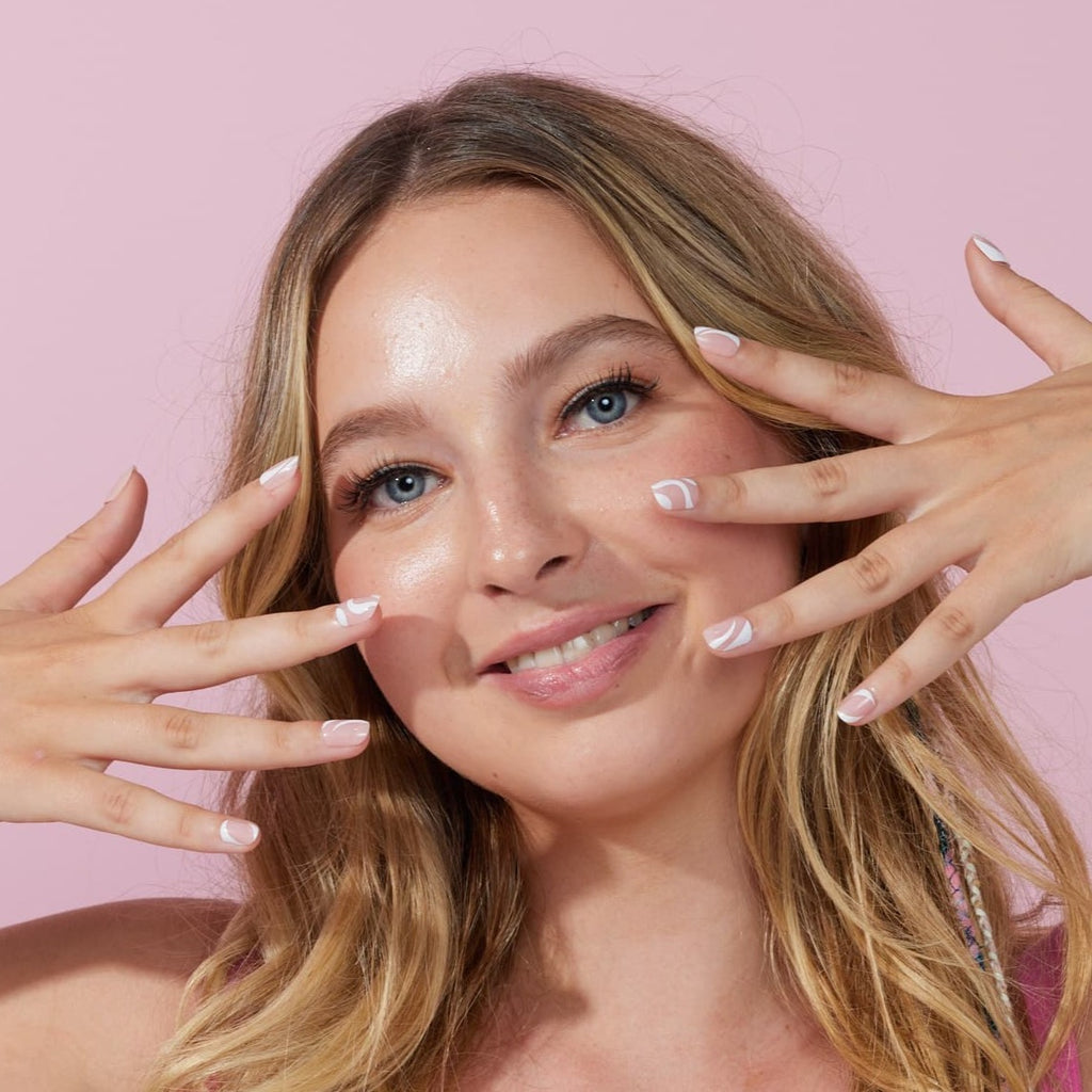 Girl wearing Instant Mani Cloud 9 press on nails in   front of pink background