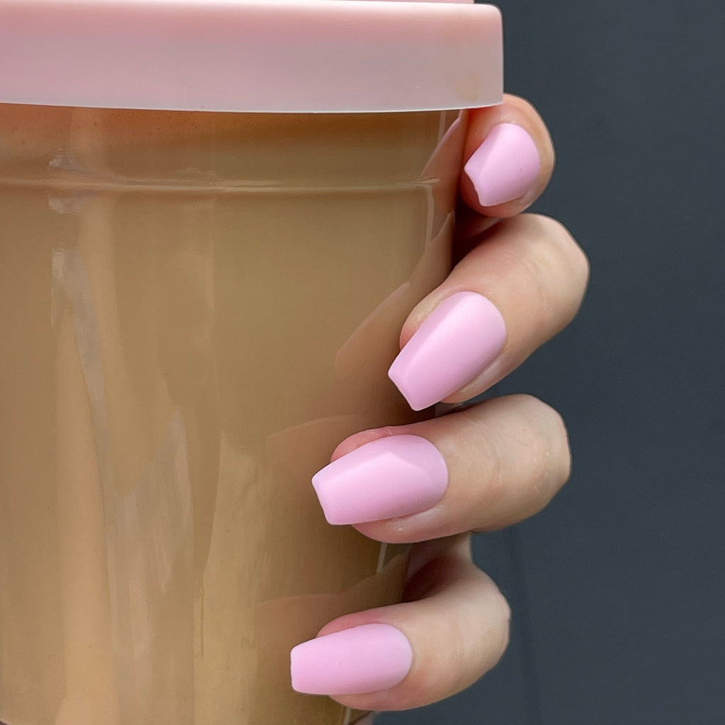 Hand wearing Instant Mani Co. pink matte nails while holding pink coffee cup 