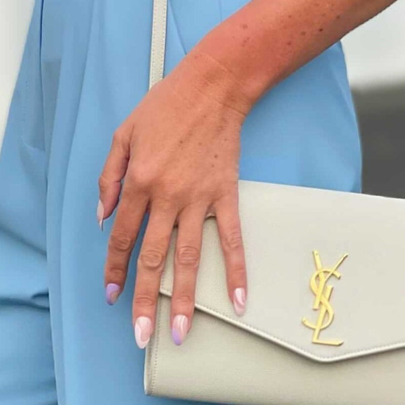 Girl wearing blue pants, with Instant Mani Co press on nails and a YSL white handbag