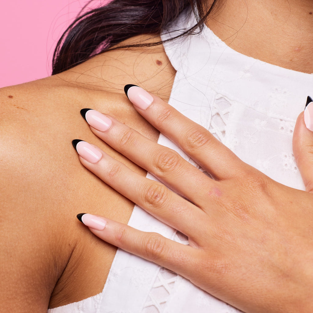 Girl in front of pink wearing black tipped Instant Mani Co. press on nails 