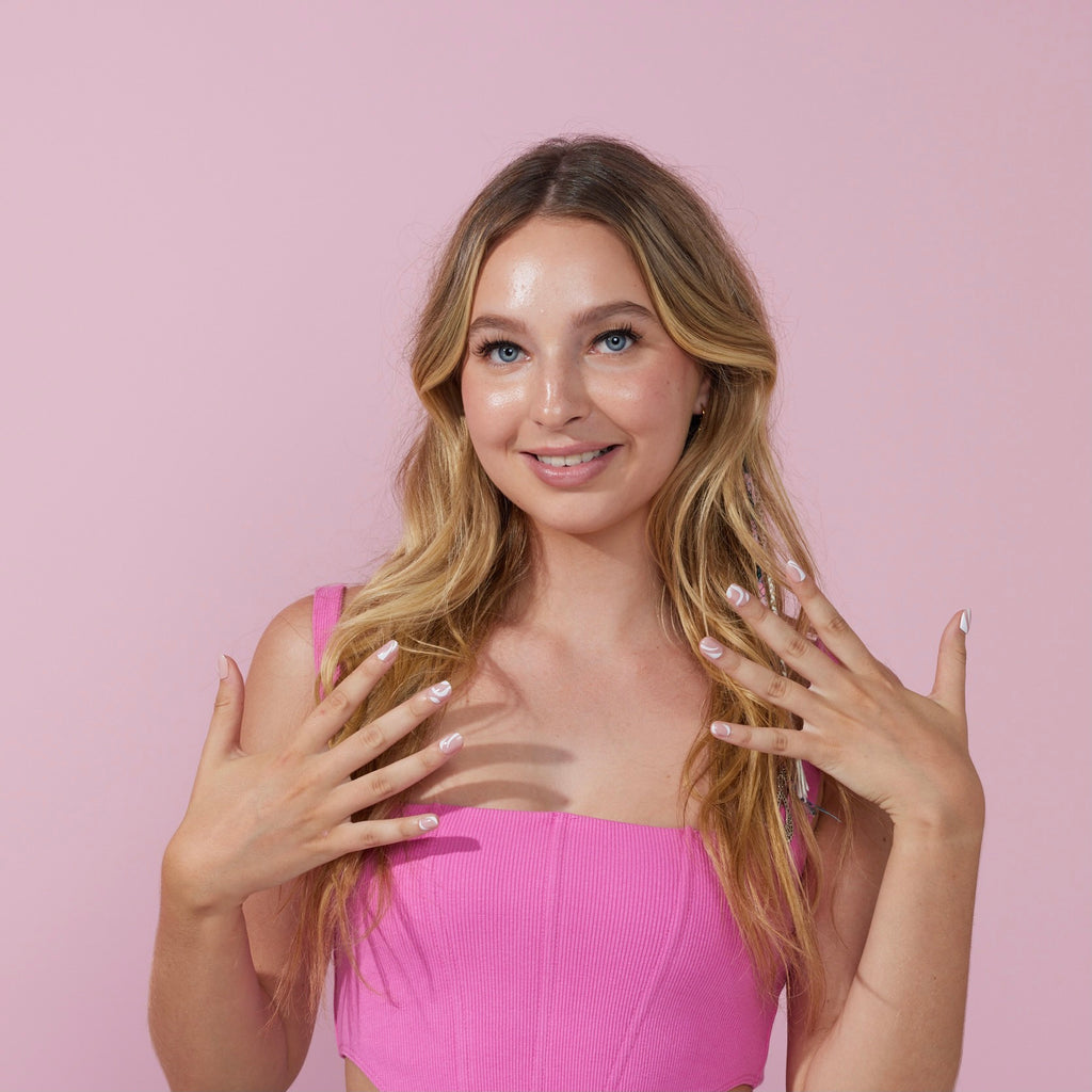 Girl standing in front of pink background wearing Instant Mani press on nails