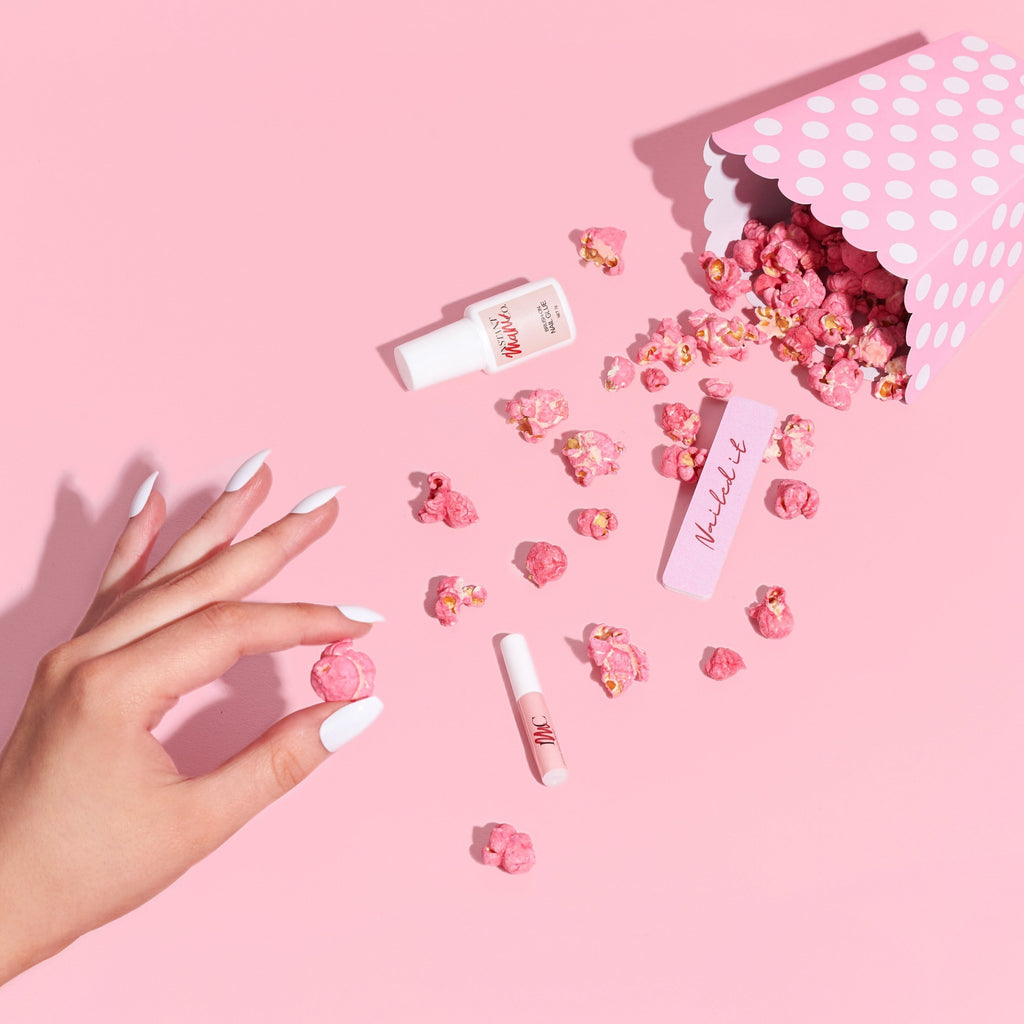 woman wearing white press-on nails reaching into popcorn case 